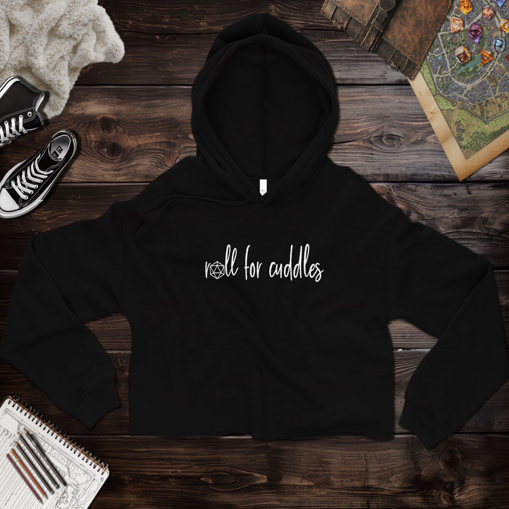 A ttrpg cropped hoodie with a playful "Roll for Cuddles" graphic, featuring a raw hem, dyed-to-match drawstrings, and a relaxed fit. Made from a super soft blend of 52% airlume combed and ring-spun cotton and 48% poly fleece, this hoodie combines comfort and style for tabletop RPG fans. The dropped shoulder design gives it a casual, modern look. Perfect for casual outings or cozy gaming sessions.