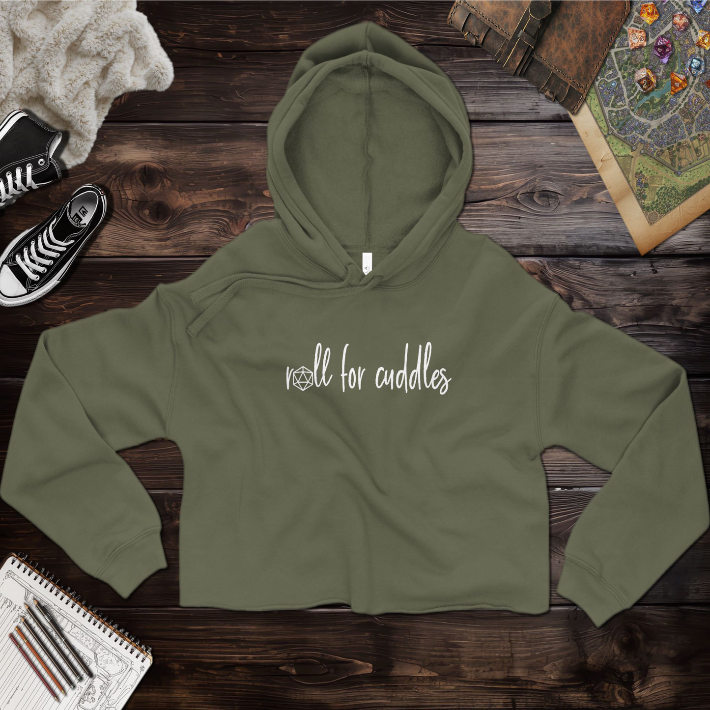 A ttrpg cropped hoodie with a playful "Roll for Cuddles" graphic, featuring a raw hem, dyed-to-match drawstrings, and a relaxed fit. Made from a super soft blend of 52% airlume combed and ring-spun cotton and 48% poly fleece, this hoodie combines comfort and style for tabletop RPG fans. The dropped shoulder design gives it a casual, modern look. Perfect for casual outings or cozy gaming sessions.