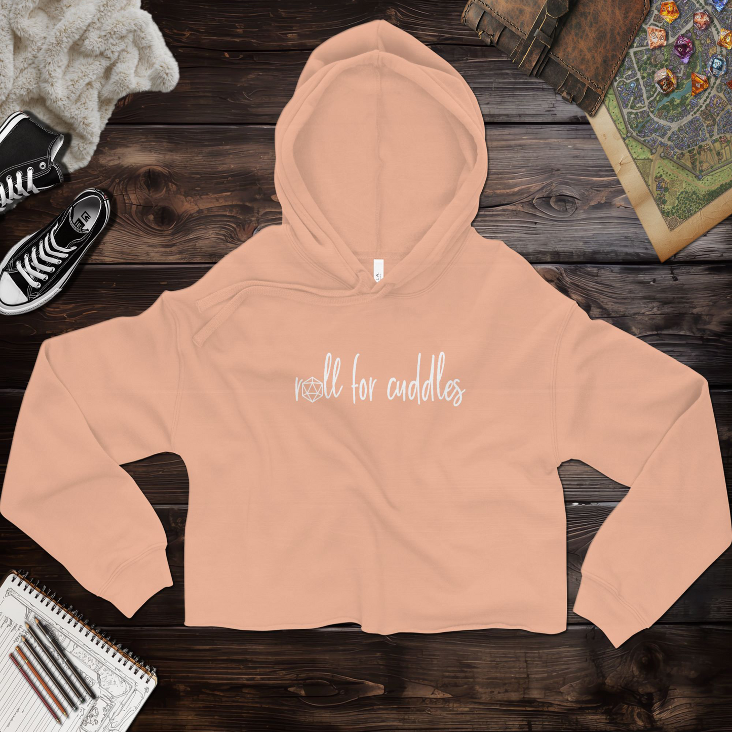 A ttrpg cropped hoodie with a playful "Roll for Cuddles" graphic, featuring a raw hem, dyed-to-match drawstrings, and a relaxed fit. Made from a super soft blend of 52% airlume combed and ring-spun cotton and 48% poly fleece, this hoodie combines comfort and style for tabletop RPG fans. The dropped shoulder design gives it a casual, modern look. Perfect for casual outings or cozy gaming sessions.